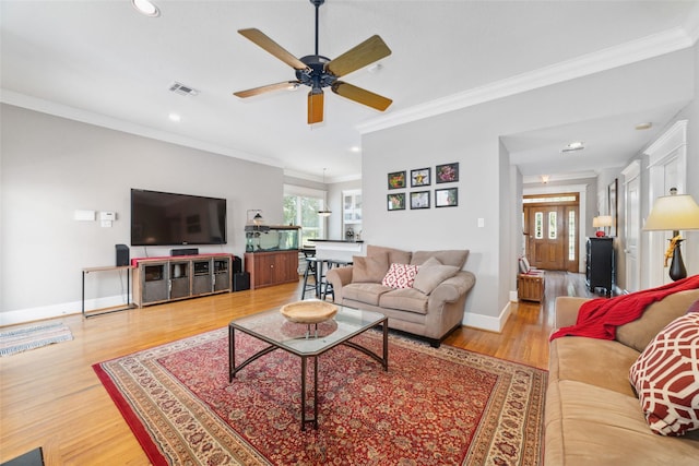 living area with recessed lighting, visible vents, light wood-style floors, ornamental molding, and baseboards