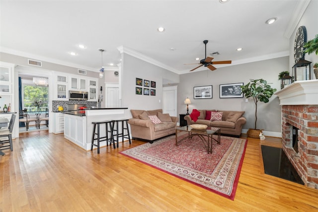 living area featuring visible vents, a fireplace, and light wood-style flooring