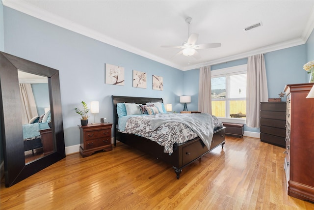 bedroom featuring ornamental molding, light wood finished floors, visible vents, and baseboards