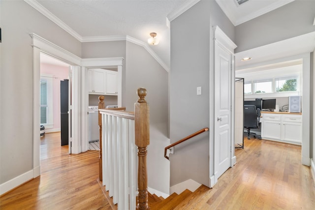 hall featuring ornamental molding, washer / clothes dryer, light wood finished floors, and an upstairs landing