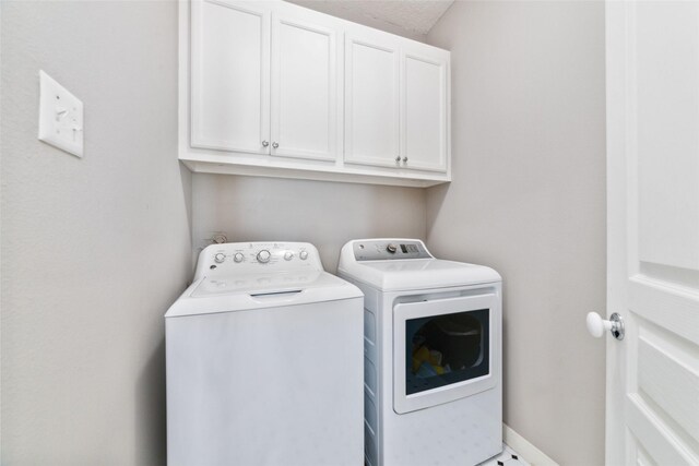 washroom with washer and clothes dryer, cabinet space, and baseboards