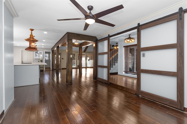 unfurnished living room featuring a barn door, a ceiling fan, and dark wood-type flooring