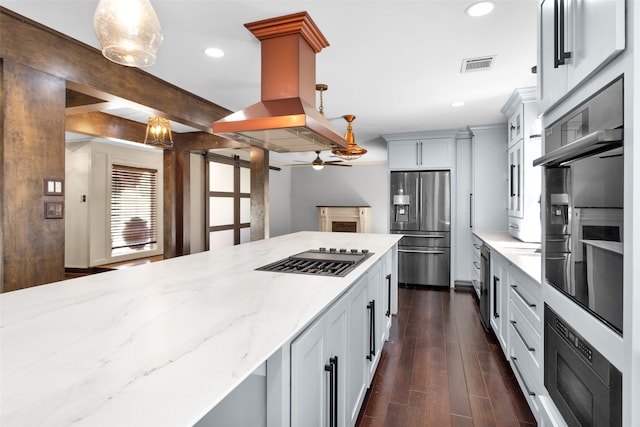 kitchen with island range hood, stainless steel appliances, dark wood-style flooring, visible vents, and light stone countertops