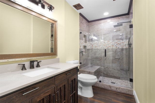 bathroom featuring toilet, wood finished floors, vanity, ornamental molding, and a stall shower