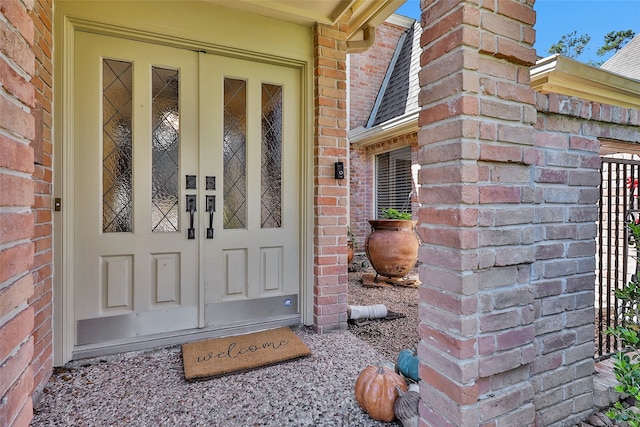 view of exterior entry with a shingled roof and brick siding