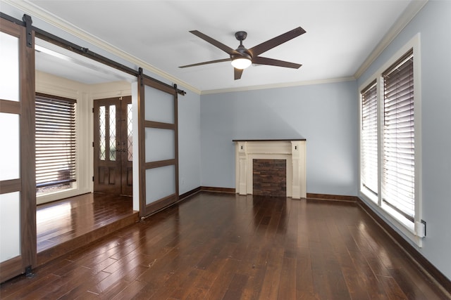 unfurnished living room featuring crown molding, a barn door, ceiling fan, wood finished floors, and baseboards