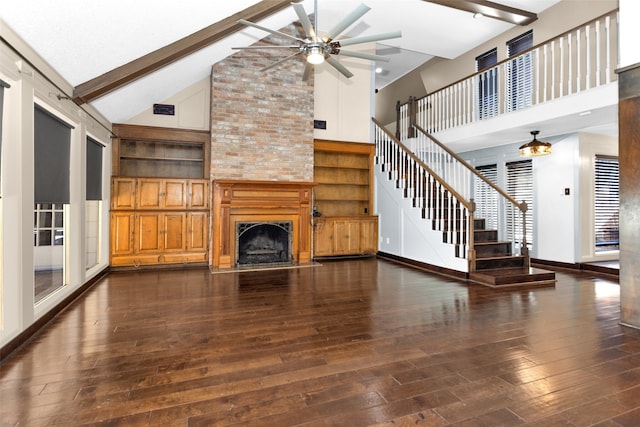 unfurnished living room with a large fireplace, visible vents, stairway, beam ceiling, and hardwood / wood-style floors