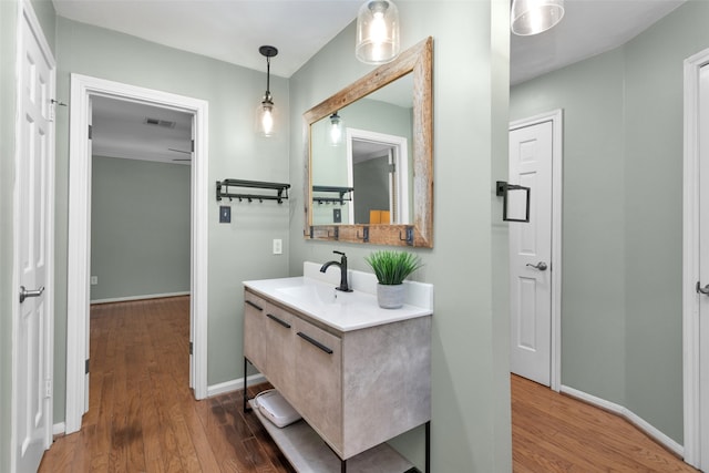 bathroom with visible vents, vanity, baseboards, and wood finished floors