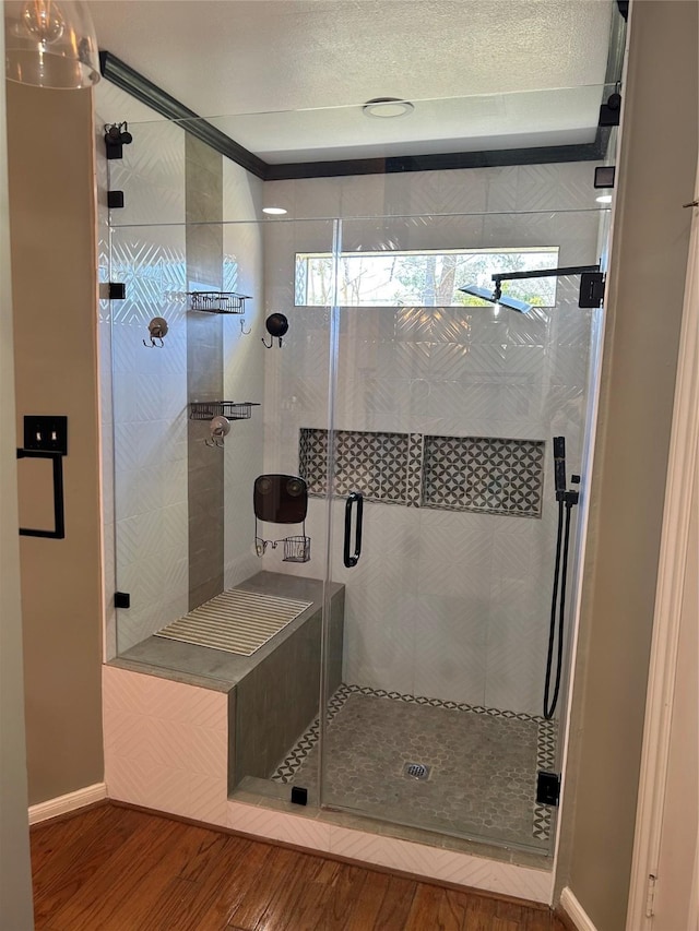 full bathroom with a stall shower, baseboards, and wood finished floors