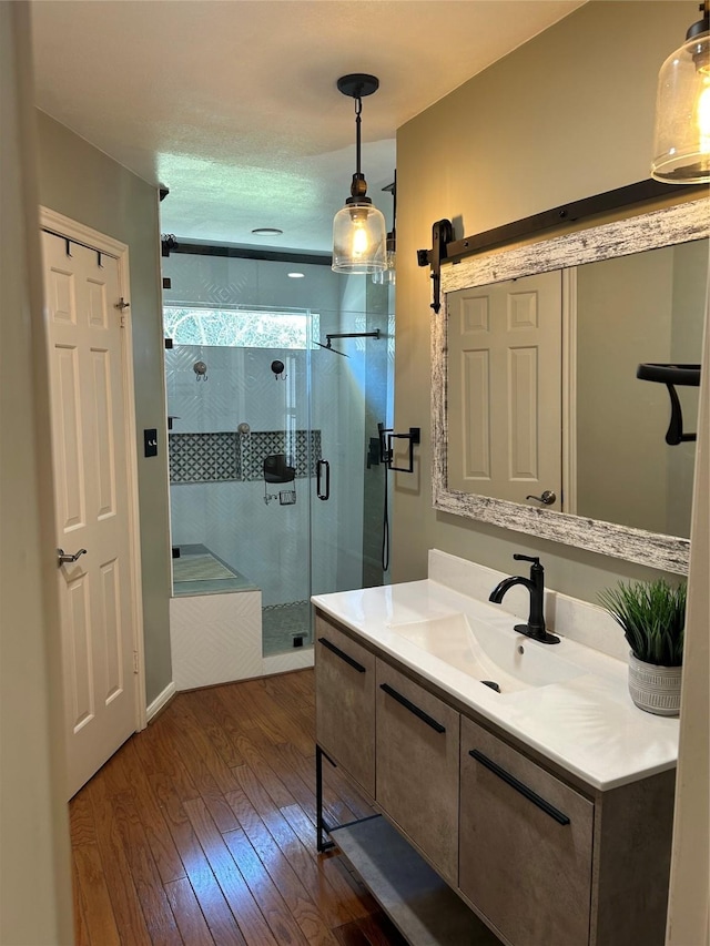 full bath featuring a stall shower, wood-type flooring, and vanity