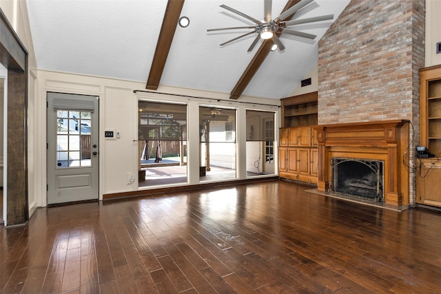 unfurnished living room featuring a ceiling fan, hardwood / wood-style floors, a textured ceiling, a fireplace, and beam ceiling