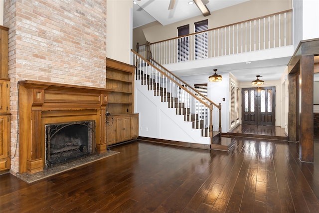 unfurnished living room featuring wood-type flooring, stairway, ceiling fan, and a high end fireplace