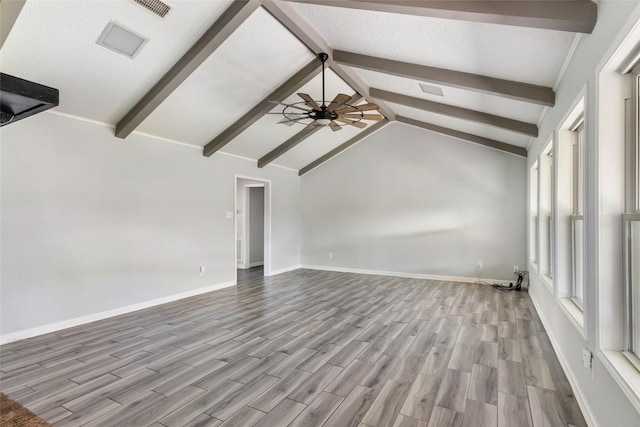 interior space with ceiling fan, vaulted ceiling with beams, wood finished floors, visible vents, and baseboards