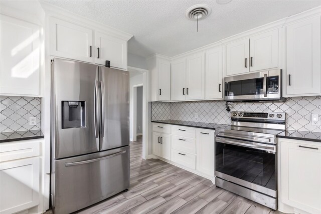 kitchen featuring dark countertops, visible vents, appliances with stainless steel finishes, and white cabinets