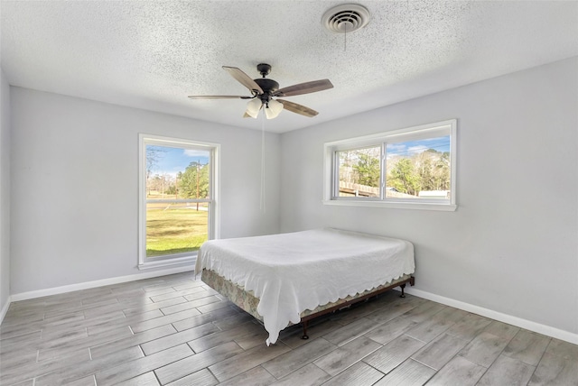 bedroom featuring multiple windows, wood finish floors, visible vents, and baseboards