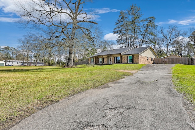 view of front of house with aphalt driveway, a front lawn, fence, and brick siding