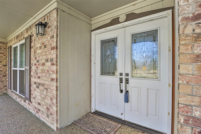 doorway to property with covered porch and brick siding