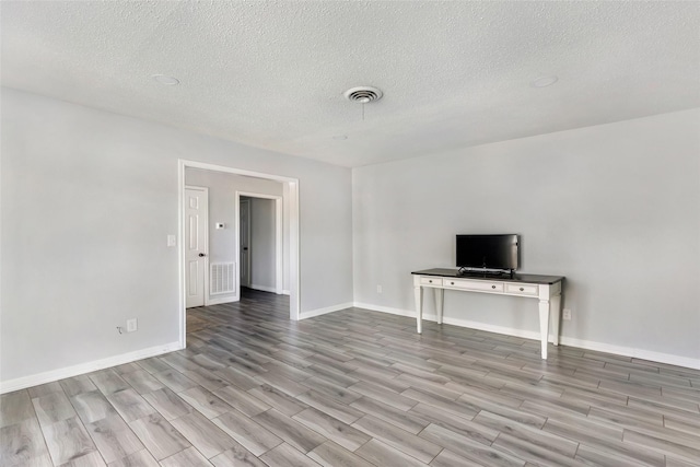 unfurnished living room featuring baseboards, visible vents, and wood finished floors