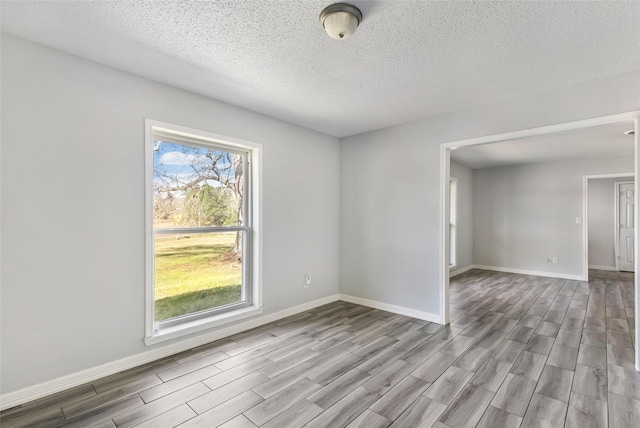 spare room with baseboards and wood finished floors