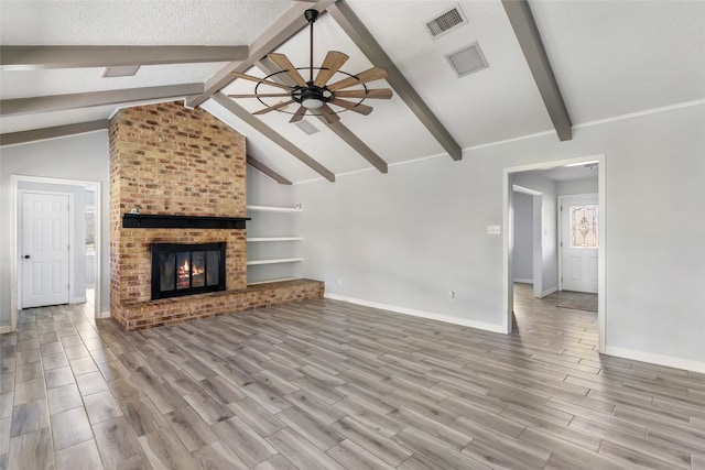 unfurnished living room featuring vaulted ceiling with beams, a fireplace, a ceiling fan, and wood finish floors