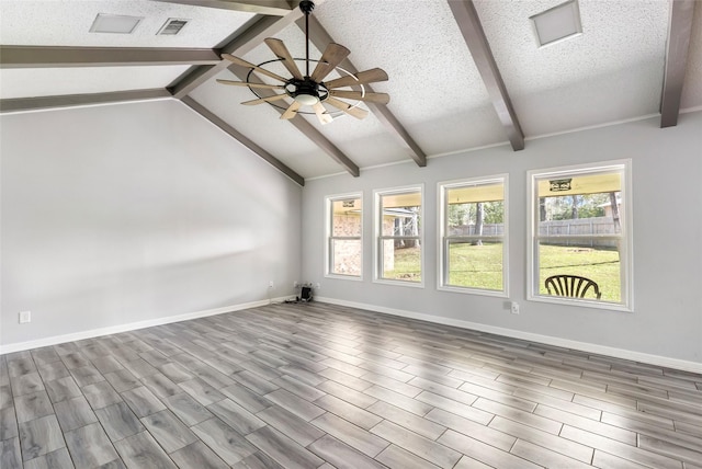 empty room featuring baseboards, visible vents, lofted ceiling with beams, wood finished floors, and a textured ceiling