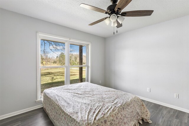 bedroom with a ceiling fan, dark wood-style flooring, a textured ceiling, and baseboards