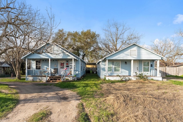 bungalow-style house with covered porch, fence, and a front yard