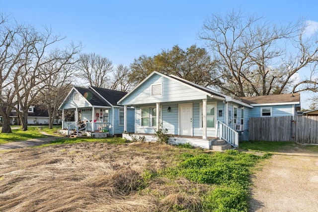 bungalow with covered porch, cooling unit, and fence