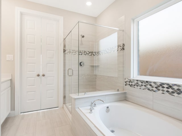 full bathroom featuring a shower stall, vanity, and a bath