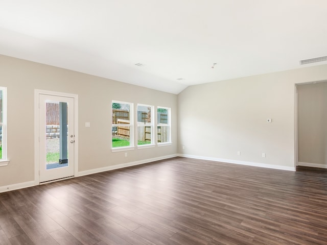 spare room featuring lofted ceiling, dark wood-type flooring, plenty of natural light, and visible vents