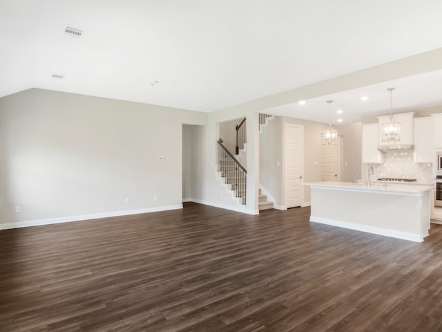 unfurnished living room featuring baseboards, visible vents, stairway, and dark wood-style flooring