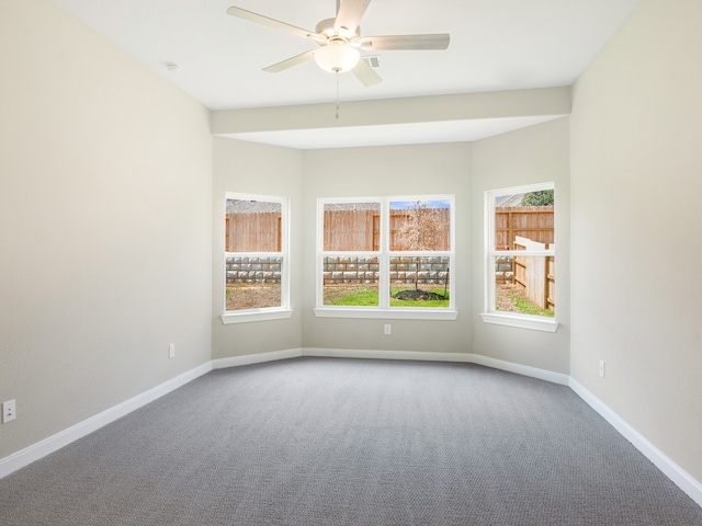 carpeted spare room with a ceiling fan and baseboards