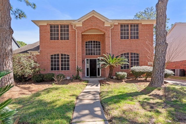 traditional home with central AC, brick siding, and a front lawn