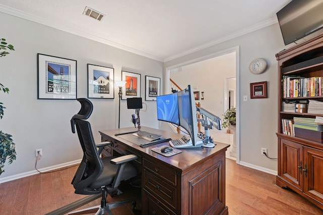 home office with baseboards, light wood-type flooring, visible vents, and crown molding