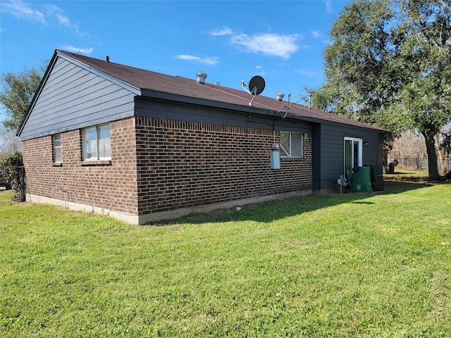 view of side of property with a yard, brick siding, and fence