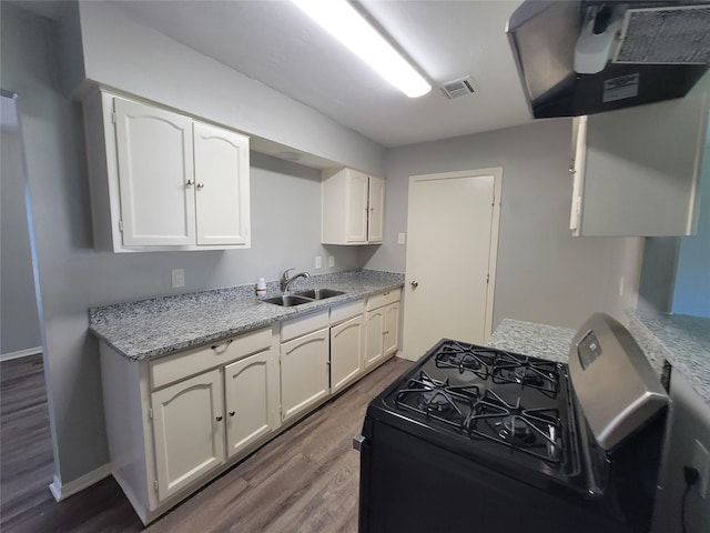 kitchen featuring visible vents, dark wood finished floors, gas range oven, white cabinetry, and a sink