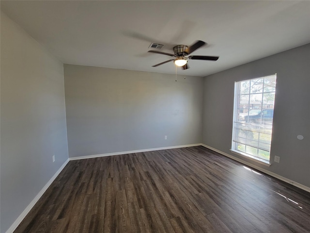 spare room featuring a ceiling fan, baseboards, visible vents, and dark wood-style flooring