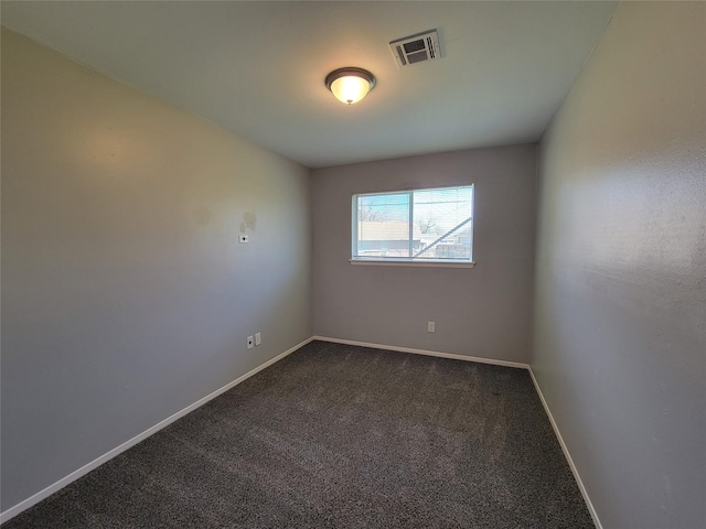 unfurnished room with baseboards, visible vents, and dark carpet