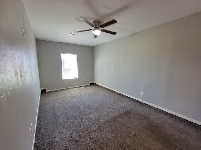 spare room with visible vents, dark carpet, baseboards, and ceiling fan