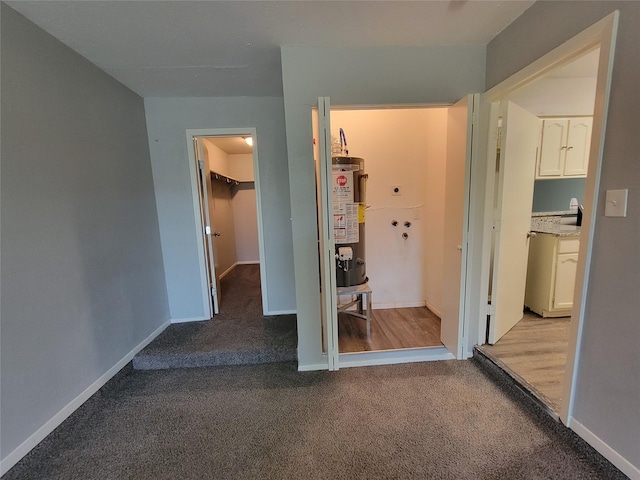 unfurnished bedroom featuring carpet flooring, baseboards, water heater, a closet, and a walk in closet