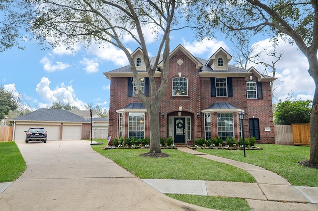 view of front of house featuring an outbuilding, brick siding, a detached garage, fence, and a front lawn