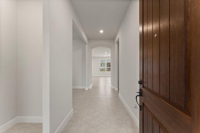 hallway with arched walkways, baseboards, and recessed lighting