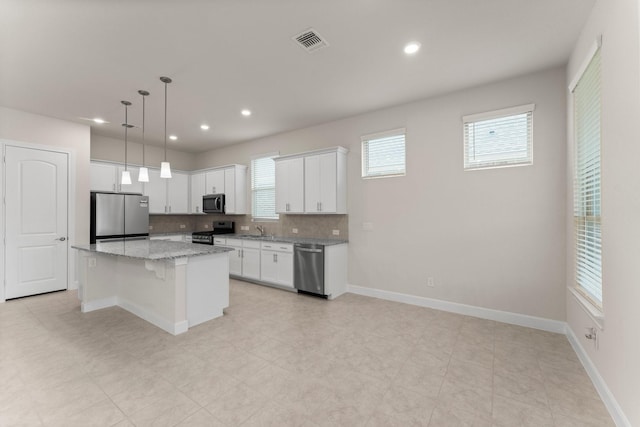 kitchen featuring a sink, visible vents, white cabinets, appliances with stainless steel finishes, and a center island