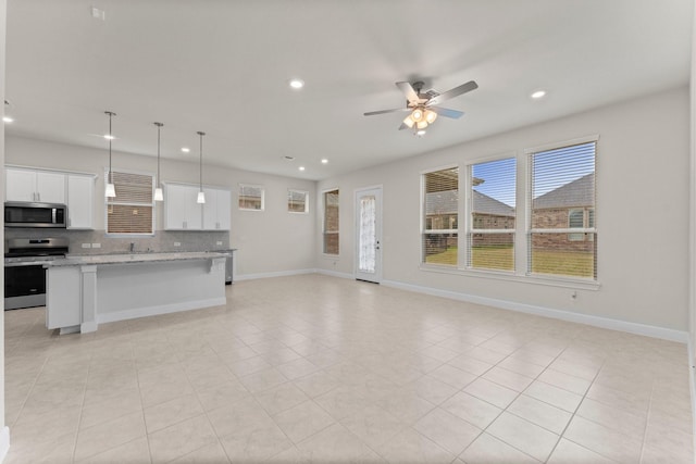 kitchen with appliances with stainless steel finishes, open floor plan, white cabinetry, and tasteful backsplash