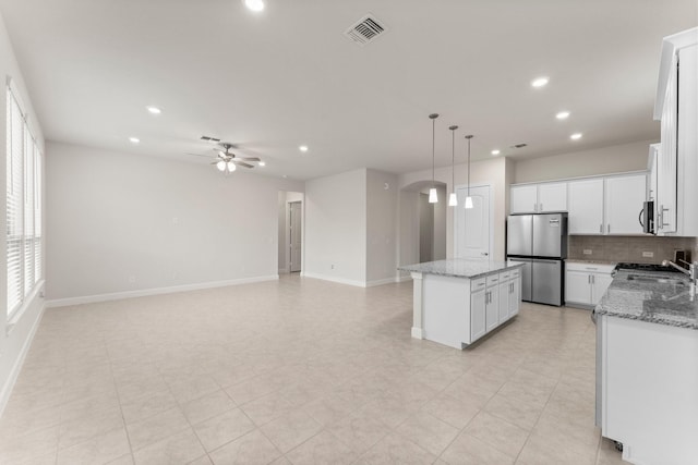 kitchen featuring tasteful backsplash, visible vents, ceiling fan, a center island, and stainless steel appliances