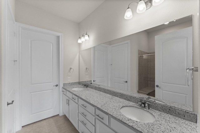 bathroom featuring double vanity, a tile shower, a sink, and tile patterned floors