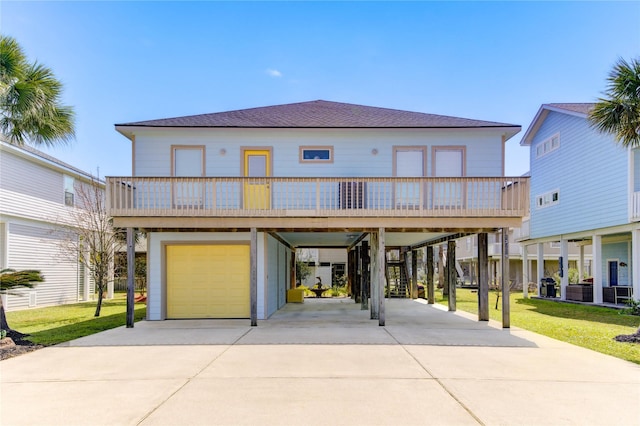 view of front facade featuring a front yard, an attached garage, a shingled roof, concrete driveway, and a carport