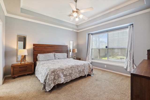 bedroom featuring light carpet, baseboards, ceiling fan, ornamental molding, and a tray ceiling