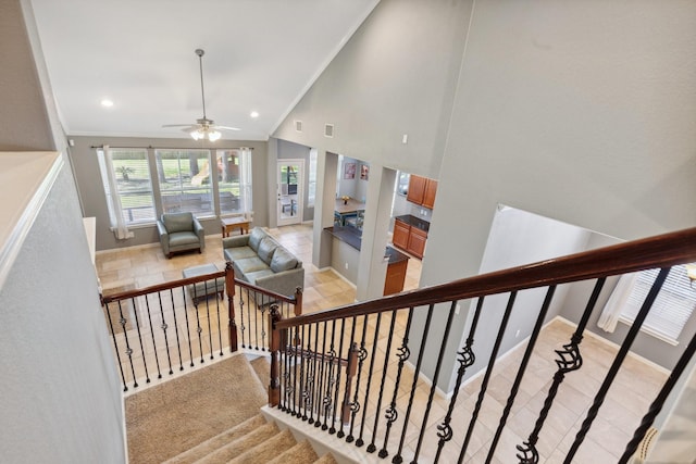 staircase with ceiling fan, high vaulted ceiling, recessed lighting, baseboards, and crown molding