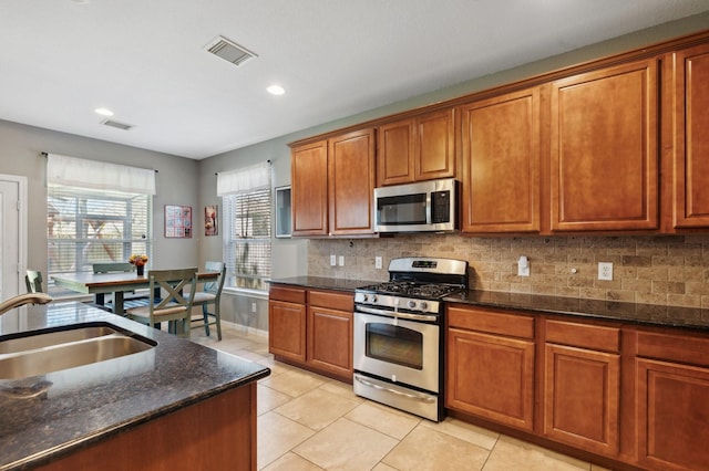 kitchen featuring a sink, visible vents, appliances with stainless steel finishes, backsplash, and brown cabinetry